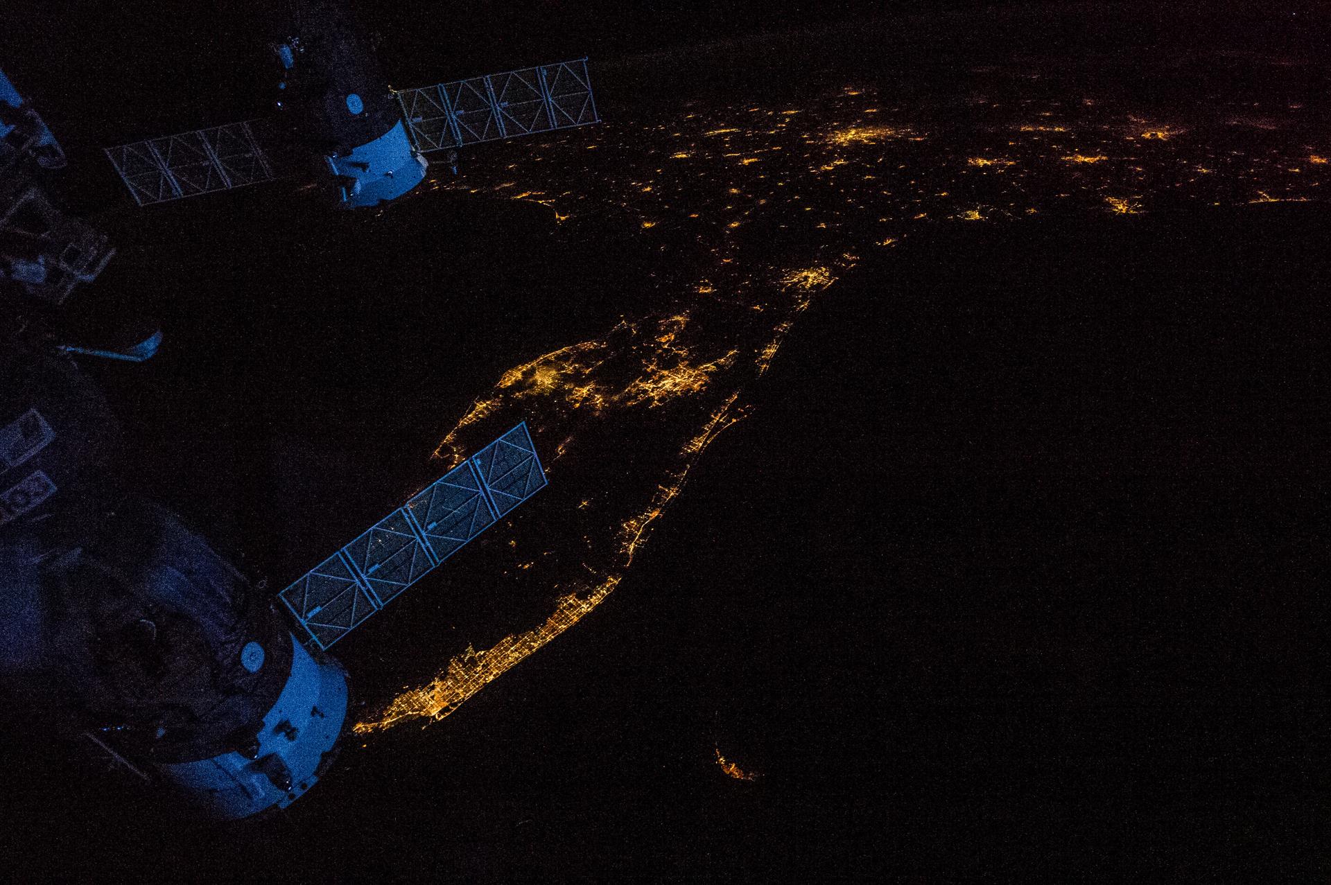 City lights at night seen from the International Space Station — the connectivity market both constellation programs are racing to serve (NASA)